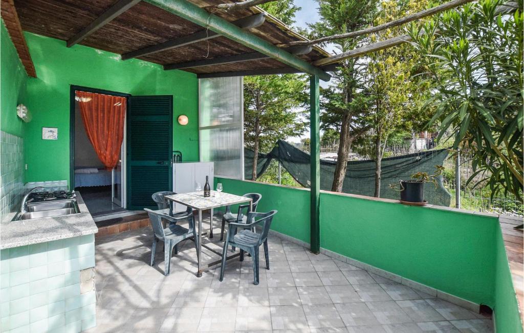 eine Terrasse mit einem Tisch und Stühlen an einer grünen Wand in der Unterkunft Lovely Home In Barano Dischia With Kitchenette in Ischia