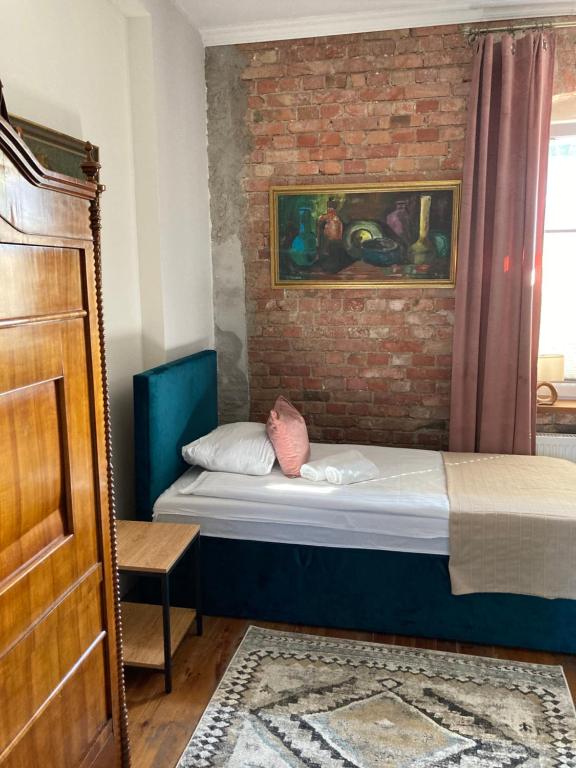 1 dormitorio con cama y pared de ladrillo en Villa Italiana pokoje z prywatnymi łazienkami & Odnowa Biologiczna, en Gdynia