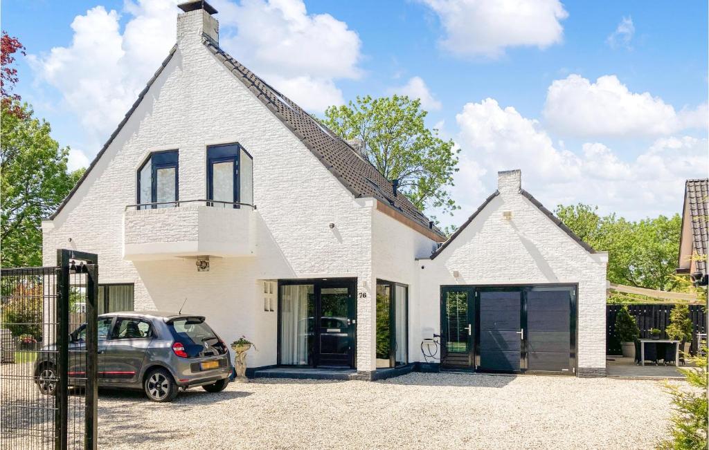 een wit huis met een auto ervoor geparkeerd bij Gorgeous Home In Bunschoten-spakenb, With Kitchen in Bunschoten