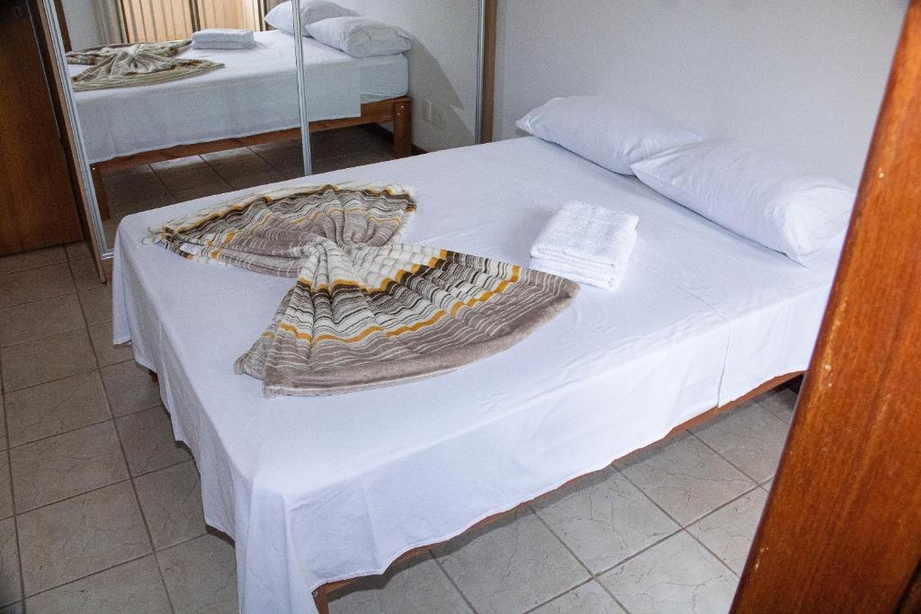 Una cama blanca con una manta encima. en Casa de 2 Suítes com Internet Rápida e Comodidades en Belo Horizonte