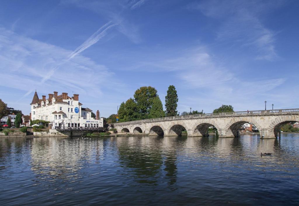 eine Brücke über einen Fluss mit einer Burg und einem Gebäude in der Unterkunft Thames Riviera Hotel, Sure Hotel Collection by Best Western in Maidenhead