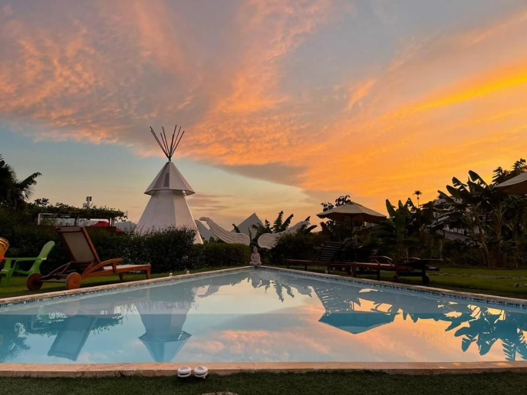 a pool at a resort with a sunset in the background at Cerro Tusa Glamping in Titiribí