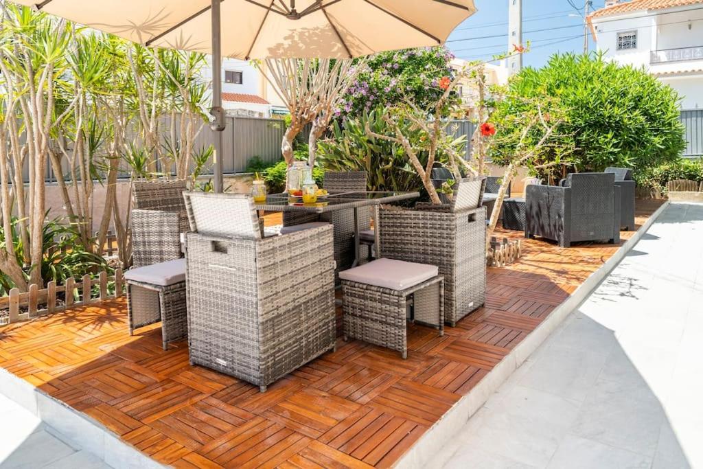 eine Terrasse mit einem Tisch, Stühlen und einem Sonnenschirm in der Unterkunft Cascais Garden Villa in Cascais