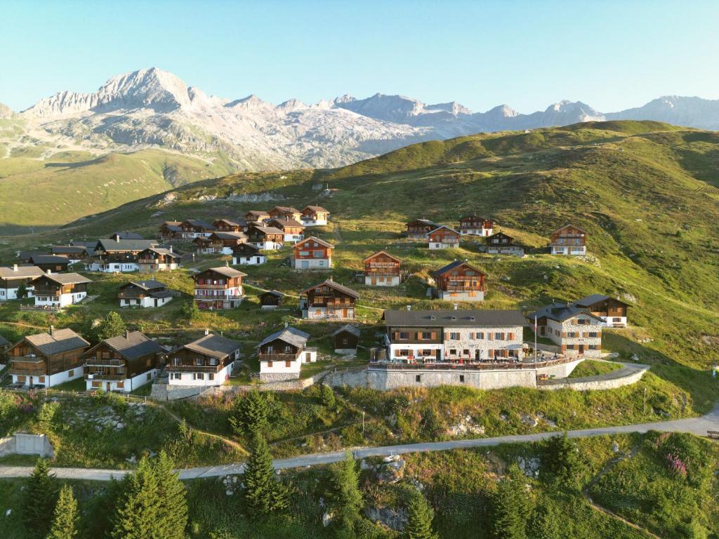 ein Dorf auf einem Hügel mit Bergen im Hintergrund in der Unterkunft Hotel Aletschhorn in Belalp