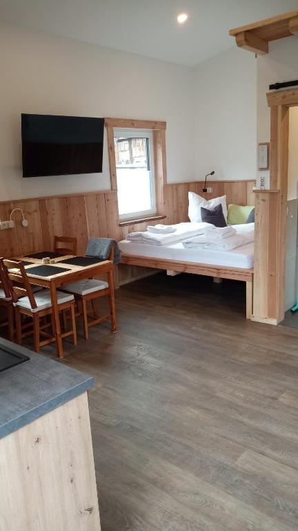 a room with a large bed and a table and chairs at Belzesaltescheune Heuboden Rhön in Riedenberg