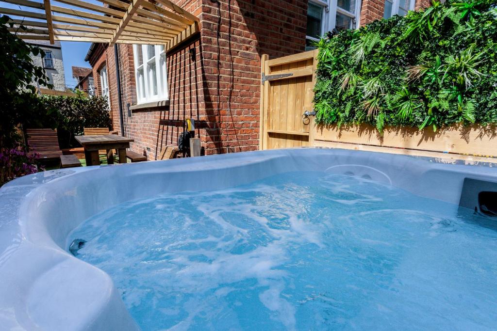 a jacuzzi tub in a yard next to a building at 1 The Old Schoolhouse for 5+cot; hot tub, parking, pets in Whitstable