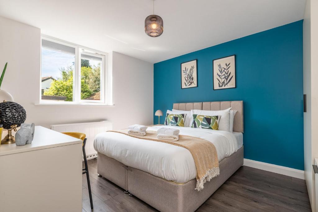 a bedroom with a blue accent wall and a bed at Must See Vibrant Contemporary Two Bed Apartment in Leicester