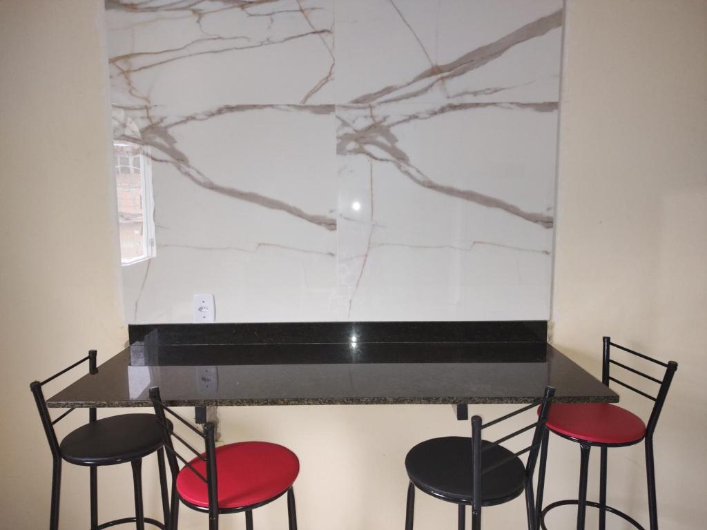 a counter with three chairs and a marble wall at 101 Apartamento em Aracruz ES in Aracruz