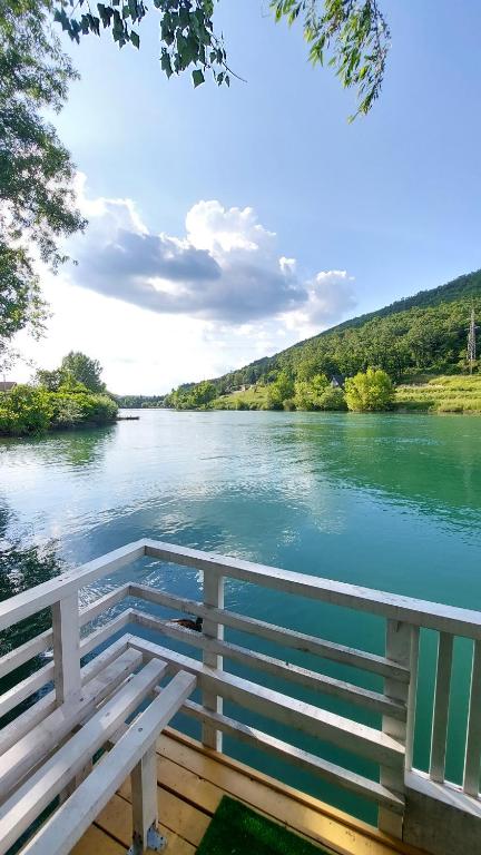 un banco blanco sentado en un muelle junto a un río en Riverside Resort Una, en Bihać