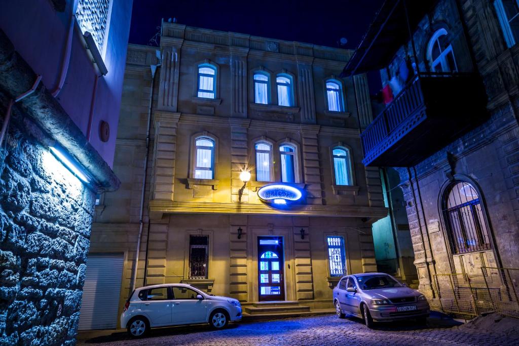 twee auto's geparkeerd voor een gebouw 's nachts bij Premier Old Gates Hotel in Baku