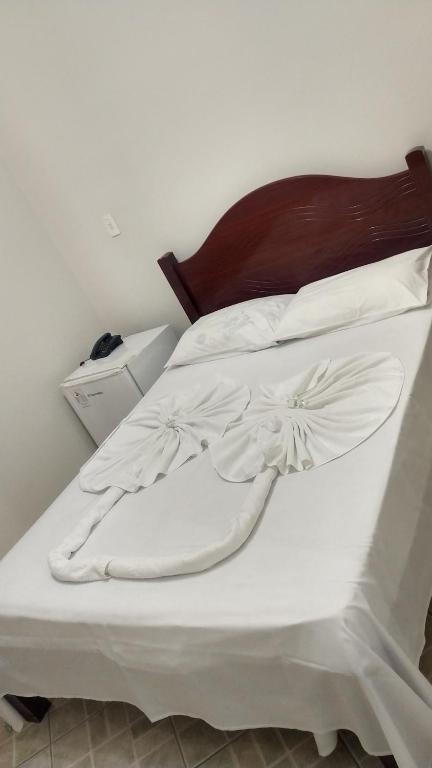 uma cama com lençóis brancos e uma cabeceira em madeira em HOTEL LÉO em Piranguinho