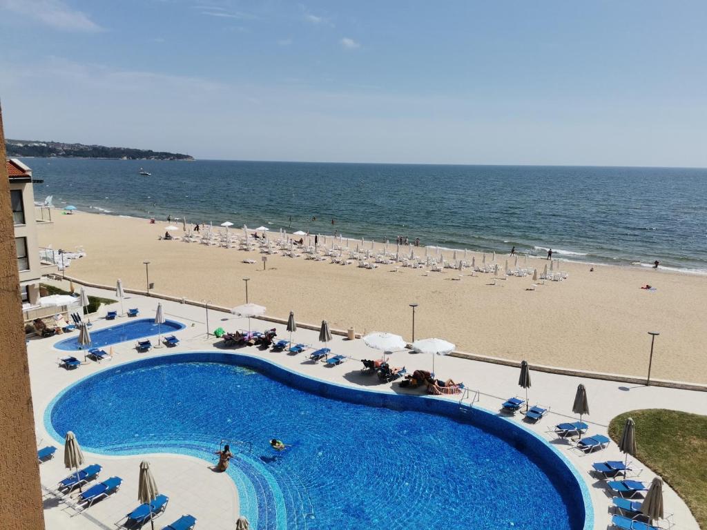 widok na plażę i basen z leżakami i parasolami w obiekcie Апартамент Б306 в Обзор Бийч Резорт на първа линия с перфектен изглед към плажа! w Obzorze