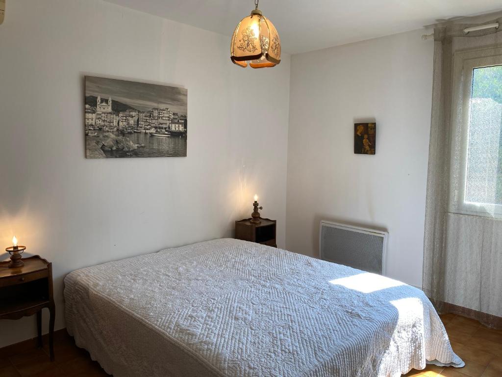 a white bedroom with a bed and a window at Casa Minnana in Figari