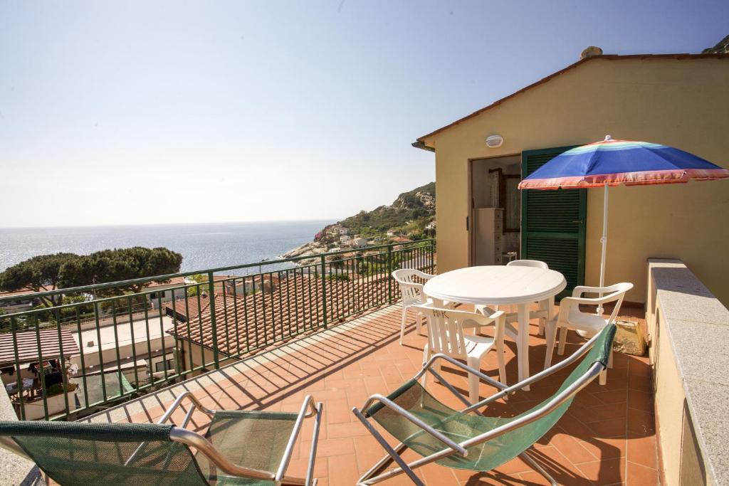 een balkon met een tafel en stoelen en een parasol bij Villetta La Terrazza in Chiessi