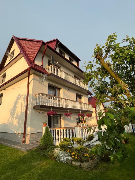 uma grande casa branca com um alpendre e escadas em Agroturystyka u Ireny em Mizerna