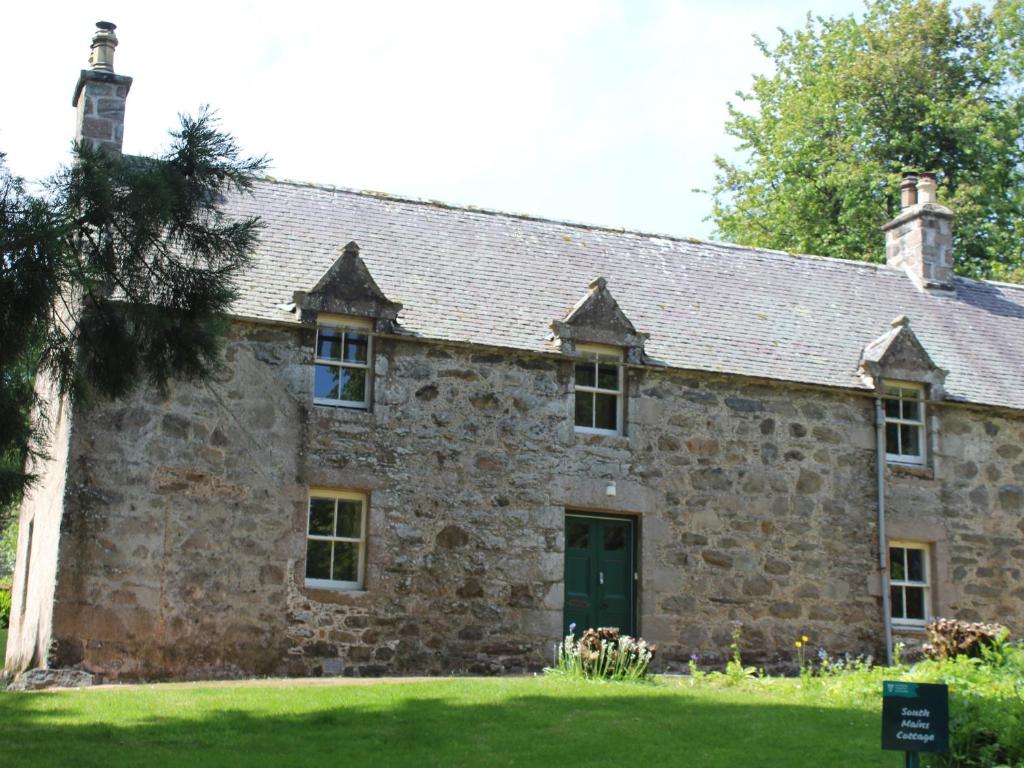 an old stone building with a green door at South Mains Cottage - Craigievar Castle in Alford