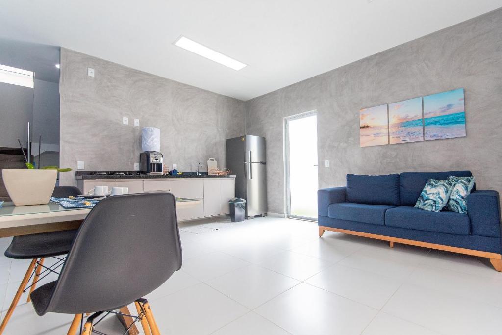 uma sala de estar com um sofá azul e uma cozinha em Pirangi Prime #05 - Triplex Vista Mar em Pirangi do Norte por Carpediem em Parnamirim