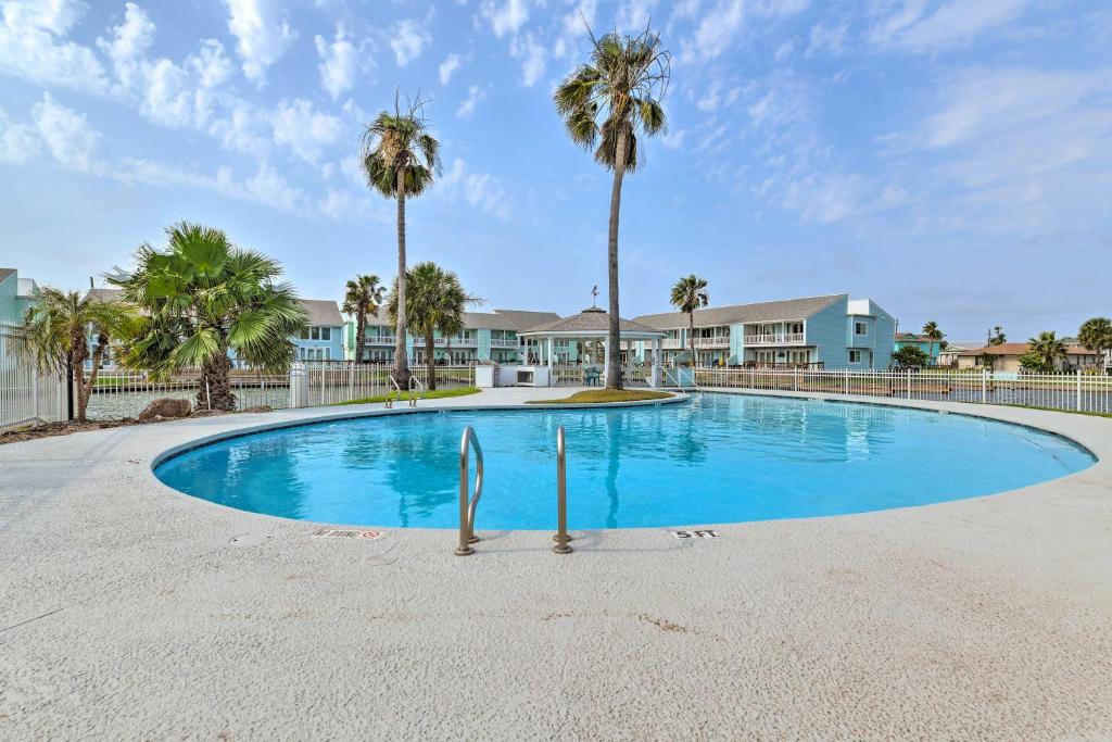 a large swimming pool with palm trees and houses at Bright Key Allegro Condo with Community Outdoor Pool in Rockport