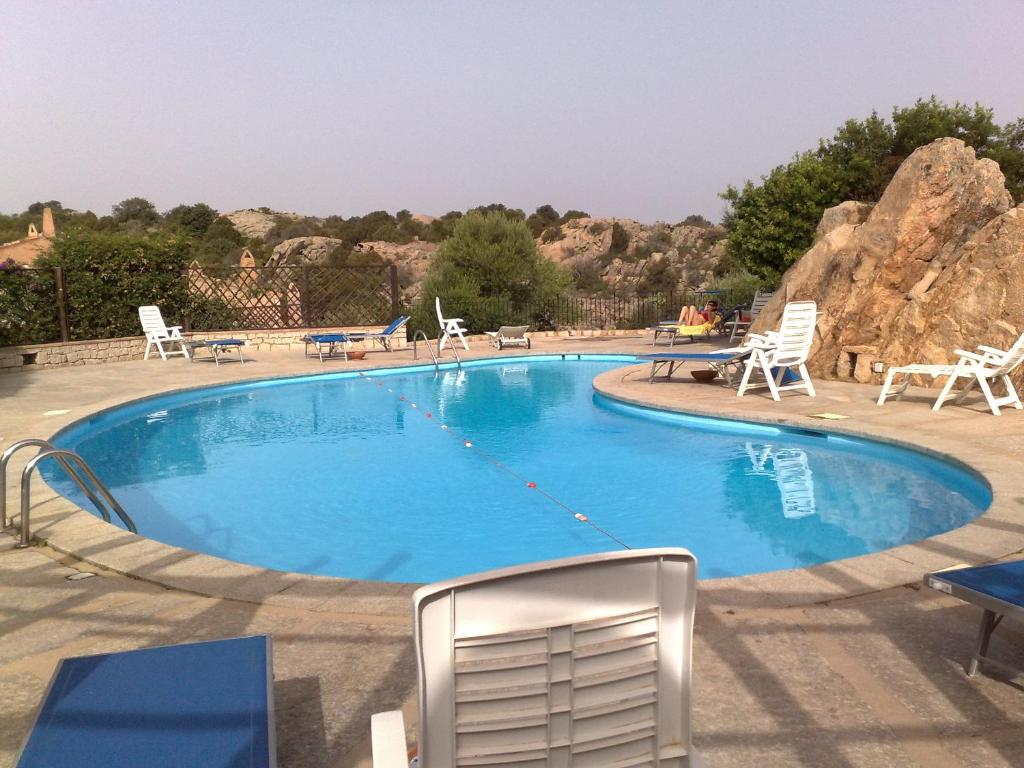 ein großer Pool mit Stühlen und einer Felsformation in der Unterkunft Apartment Alba in Porto Cervo