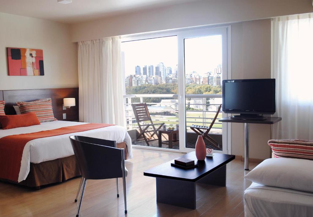 Palermo Suites Buenos Aires Apartments في بوينس آيرس: غرفة في الفندق بها سرير وتلفزيون وأريكة