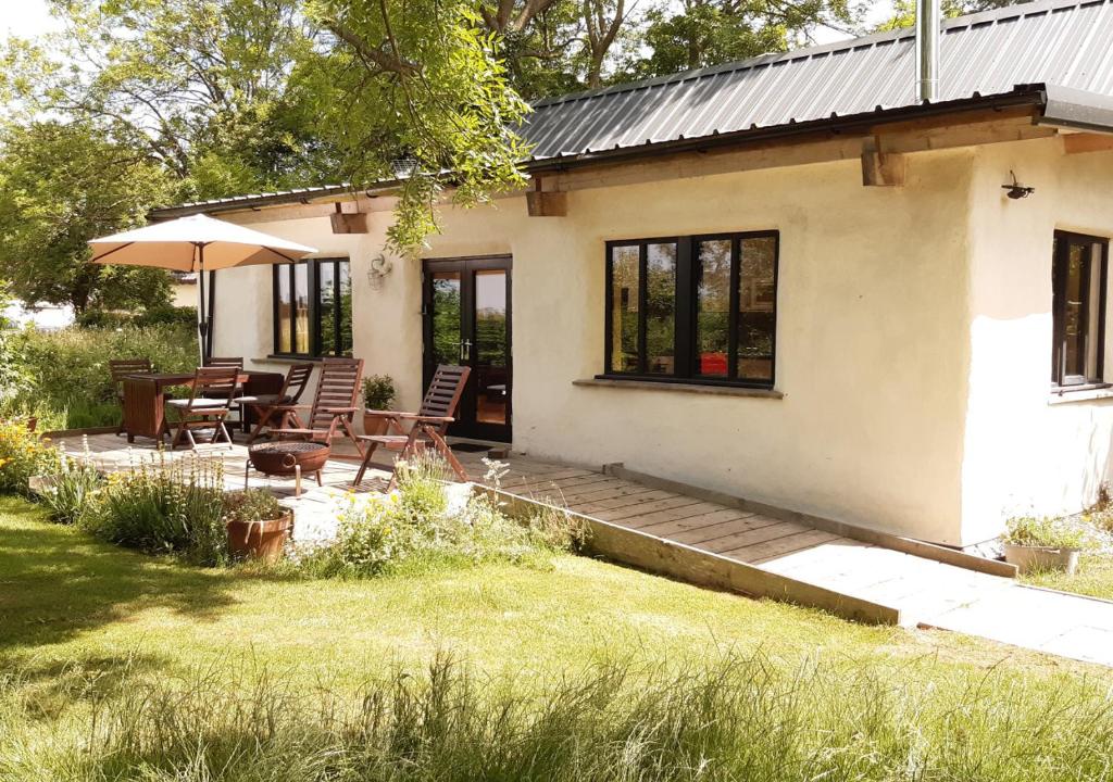 a small white house with a deck and a patio at Straw Bale Cottage in Haughley