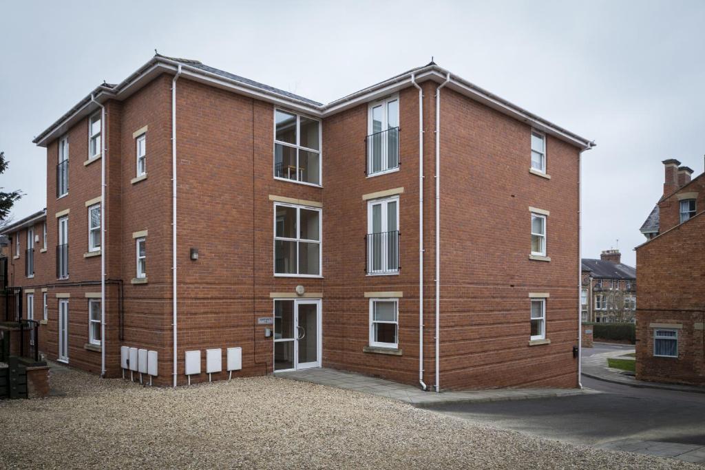 a large brick building with white windows on a street at Dashwood Apartments in Banbury