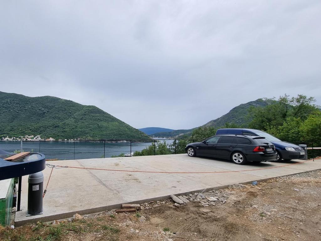 two cars parked in a parking lot next to a body of water at Casa Vita Nova in Perast