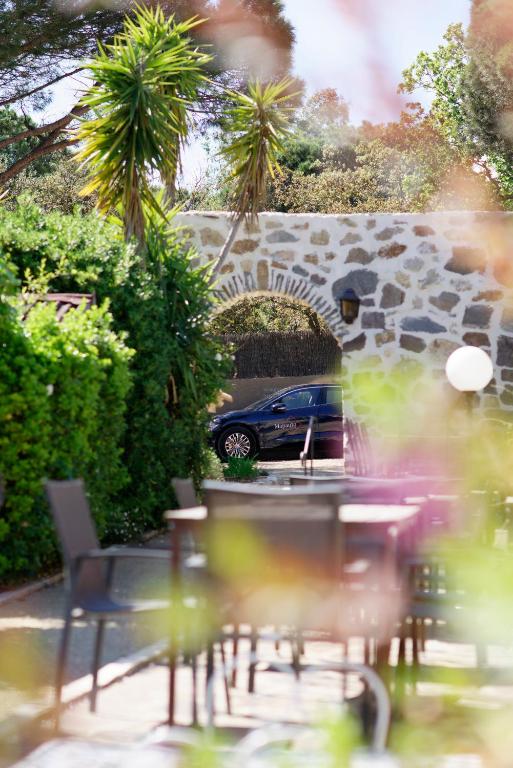 a car is parked in a parking lot with tables and chairs at La Ferme D'Augustin in Saint-Tropez