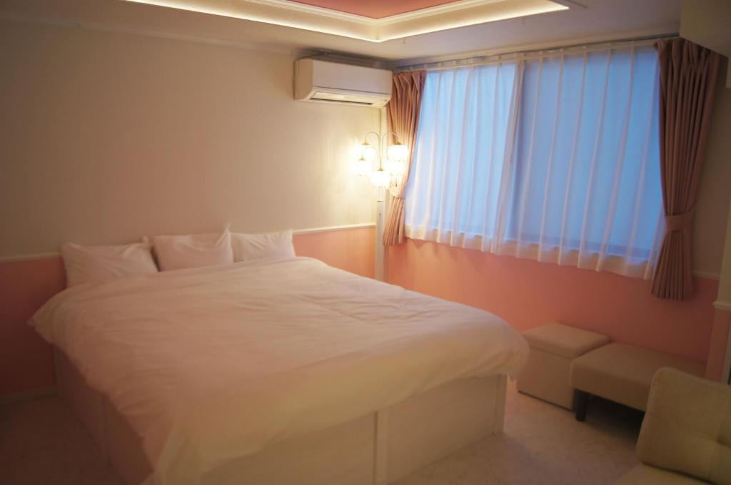 um quarto com uma cama branca e uma janela em Guest house Laule'a Tennoji - Vacation STAY 10602 em Osaka