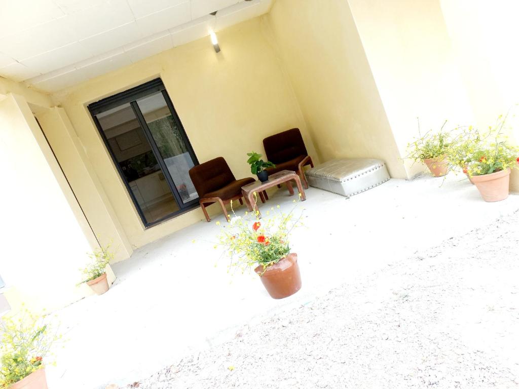 une terrasse avec 2 chaises, une fenêtre et des plantes dans l'établissement Gîte Narbonnais 13 min des plages-Jardin-Terasse-Parking, à Narbonne