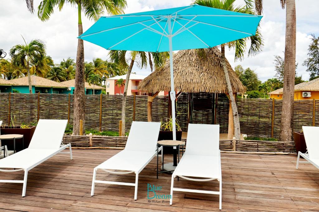 a group of chairs and an umbrella on a deck at Village Kawann - Toumalacai 246 in Grand-Bourg