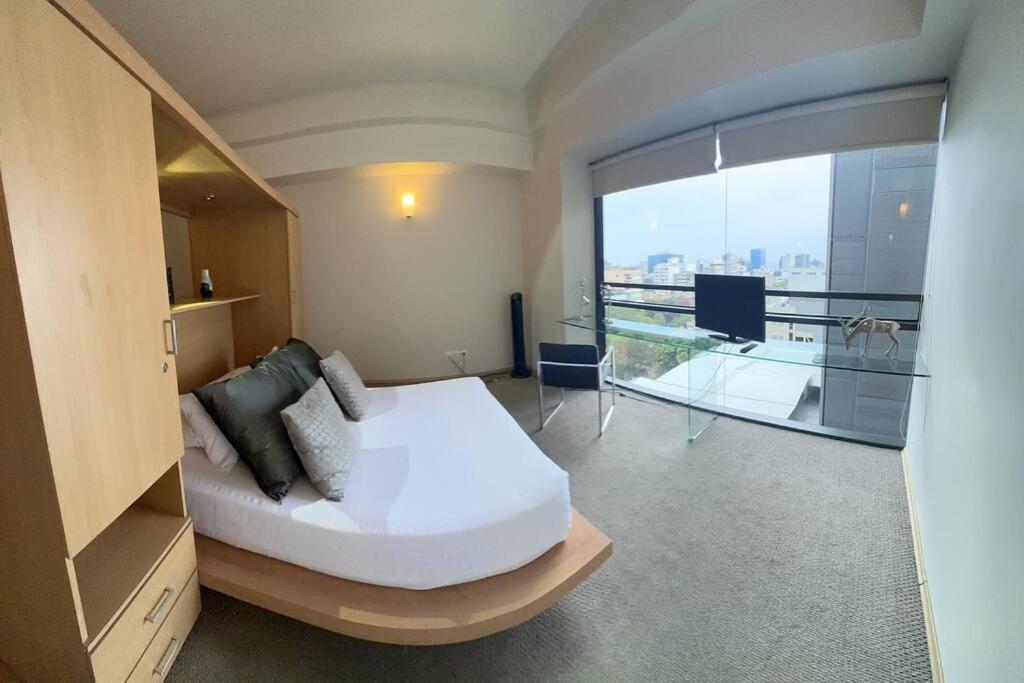 ein Schlafzimmer mit einem weißen Bett und einem großen Fenster in der Unterkunft GREAT COZY LOFT LUXORY POOL/ GYM/JACUZZI/ROOF TOP in Mexiko-Stadt