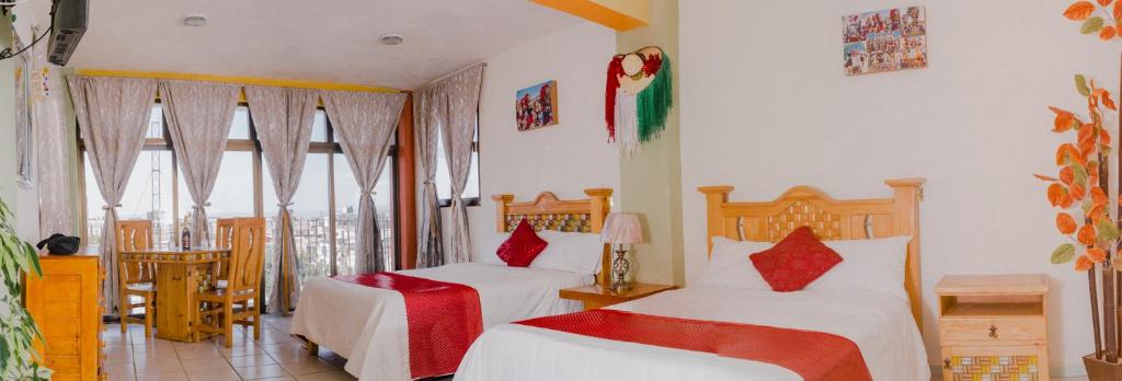 a bedroom with two beds with red pillows at Hotel Carnaval in Huejotzingo