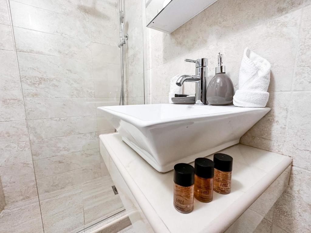 a white bathroom with a sink and a shower at Harmonia Bungalows & Pool in Sveti Stefan