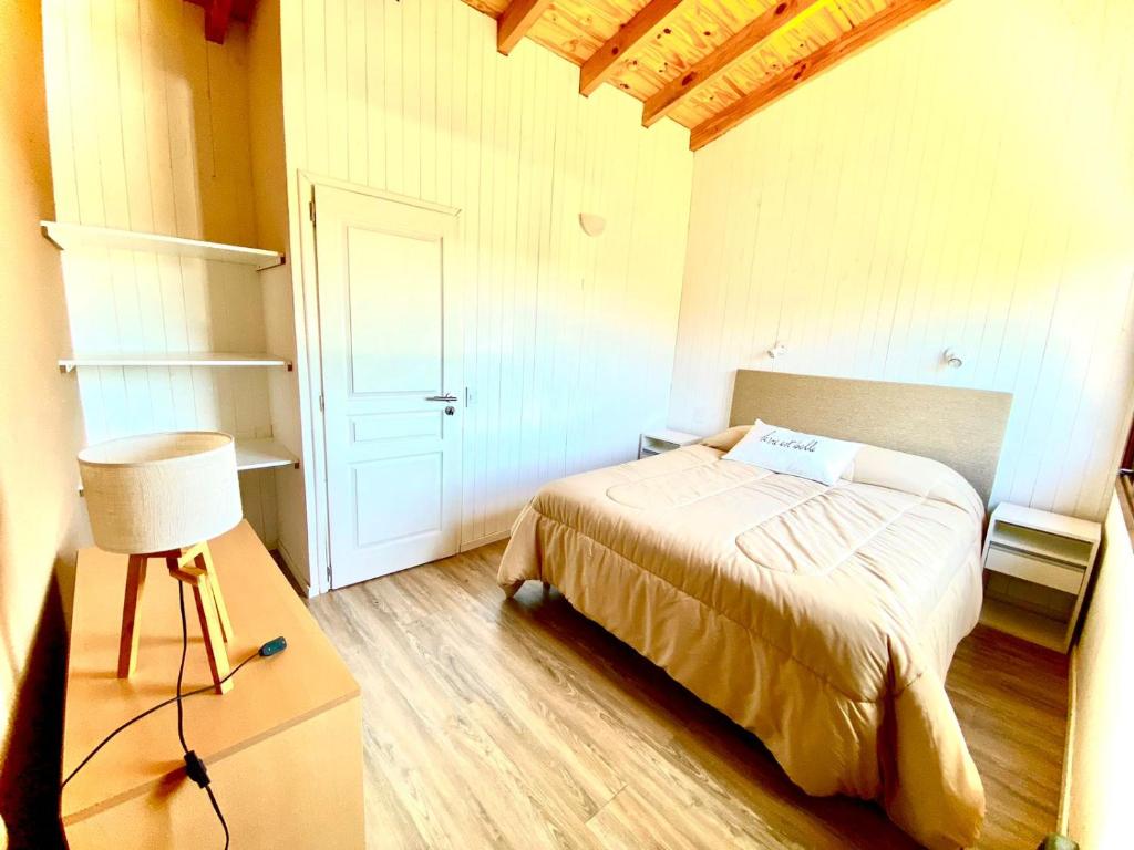 a small bedroom with a bed and a white door at Departamentos Tres Maitenes in Villa La Angostura