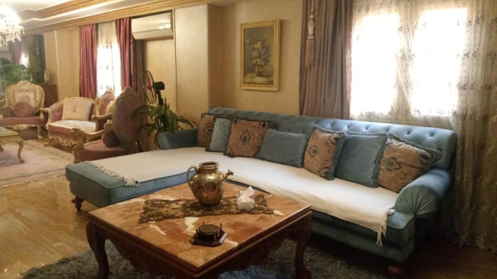 ein Wohnzimmer mit einem blauen Sofa und einem Tisch in der Unterkunft 5 Stars Apartment in Kairo