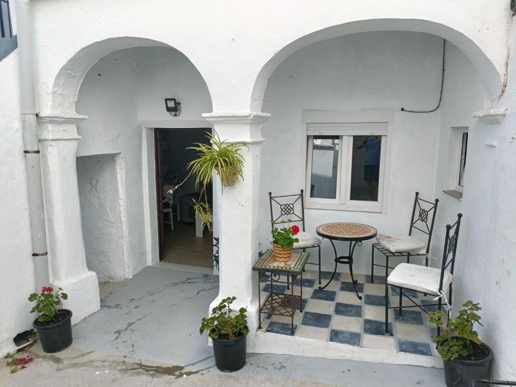 um pátio com uma mesa e cadeiras num edifício em El barrio em Medina Sidonia