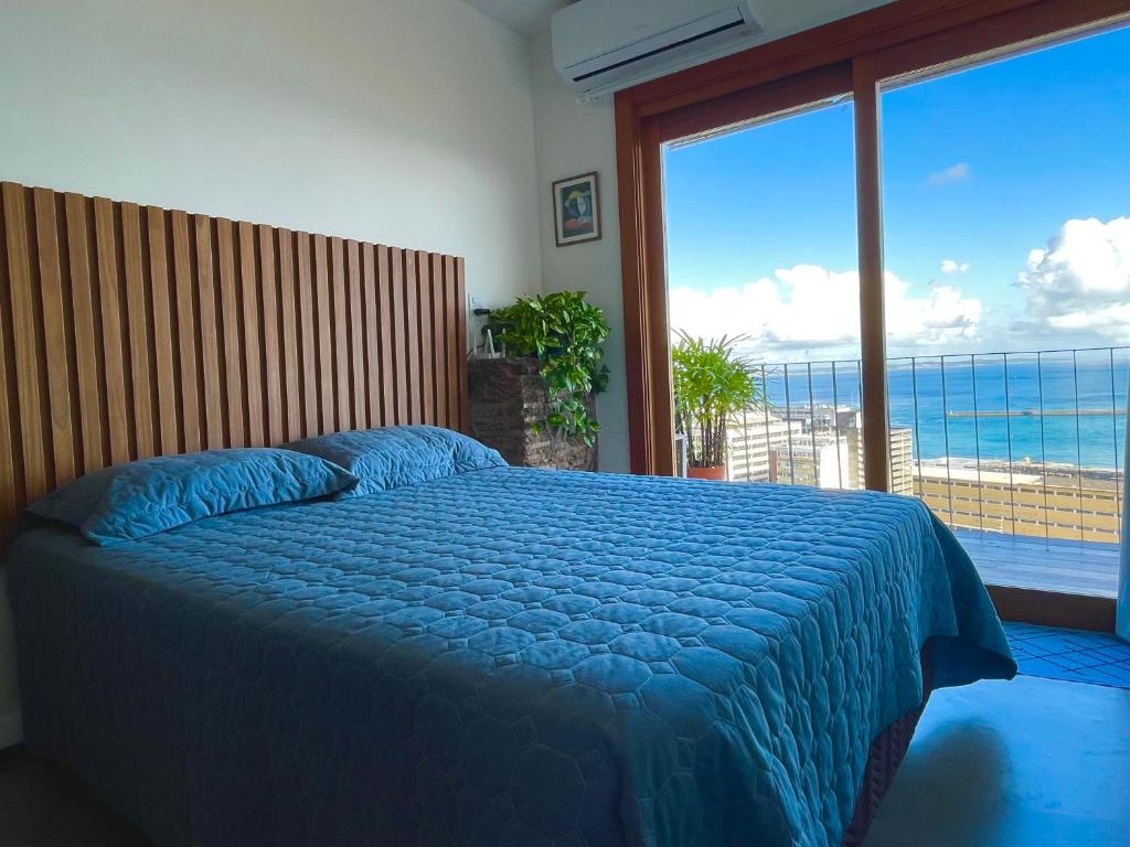 a bedroom with a bed with a view of the ocean at Studio da fonte/Vista mar in Salvador