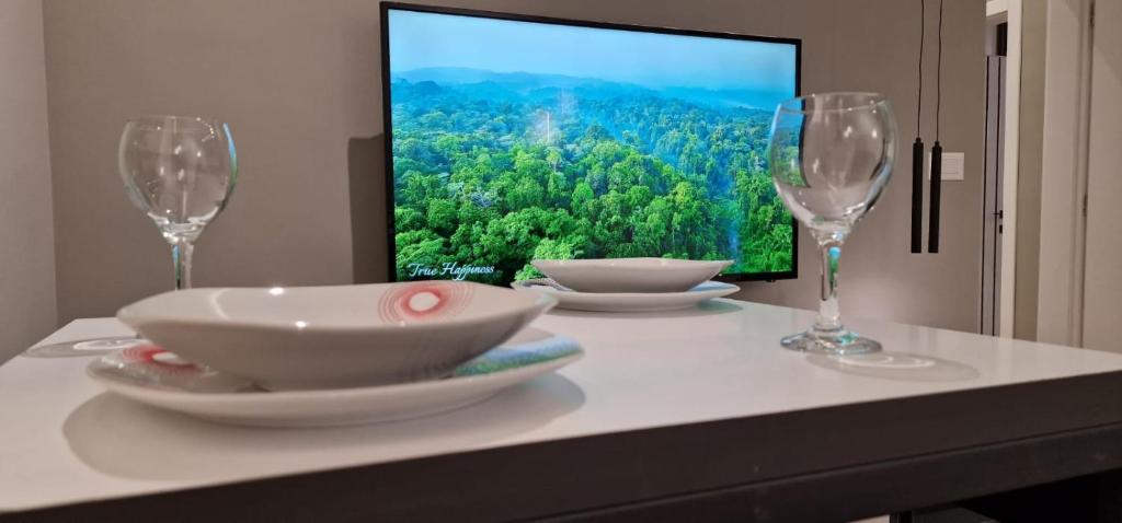 a table with two wine glasses and a television at Heart of Tirana Apartment in Tirana