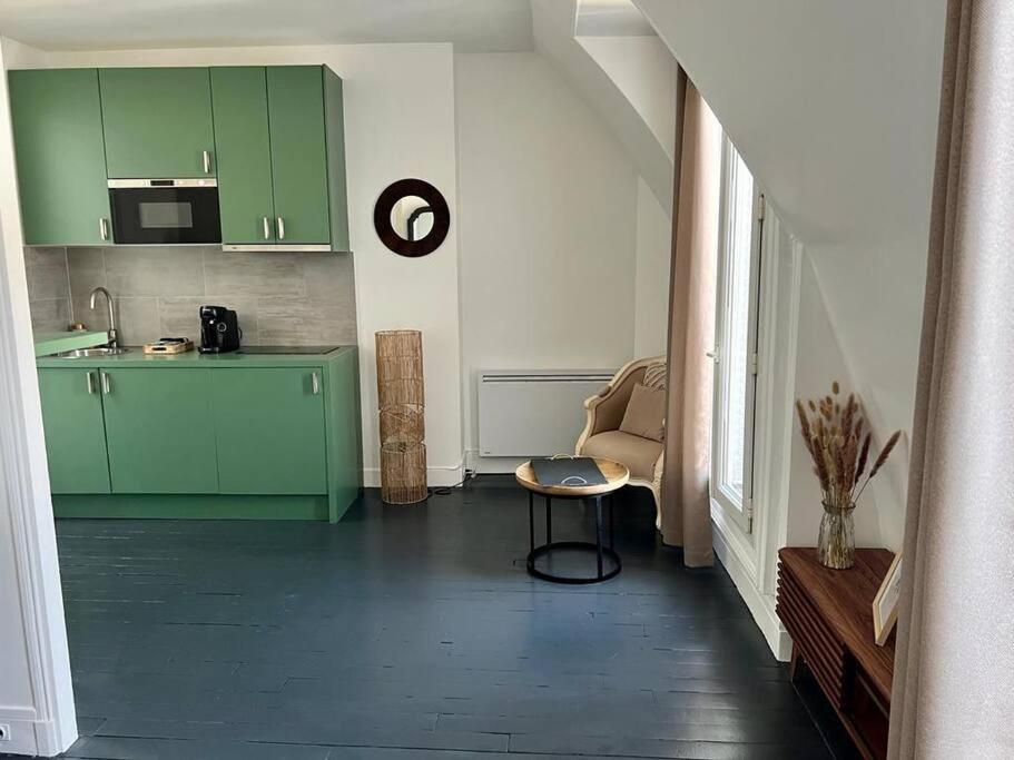 a kitchen with green cabinets and a chair in a room at Appartement cosy - Sacré coeur in Paris