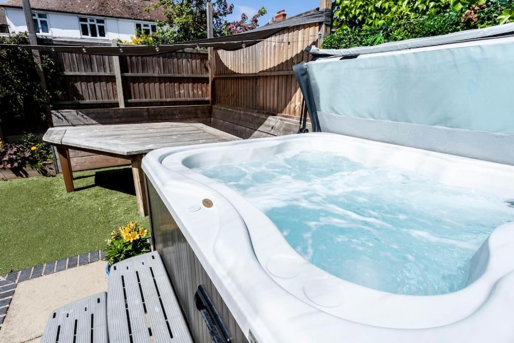 a jacuzzi tub in a backyard with a table at 3 The Old Schoolhouse: hot tub, log burner, parking, en-suite in Whitstable