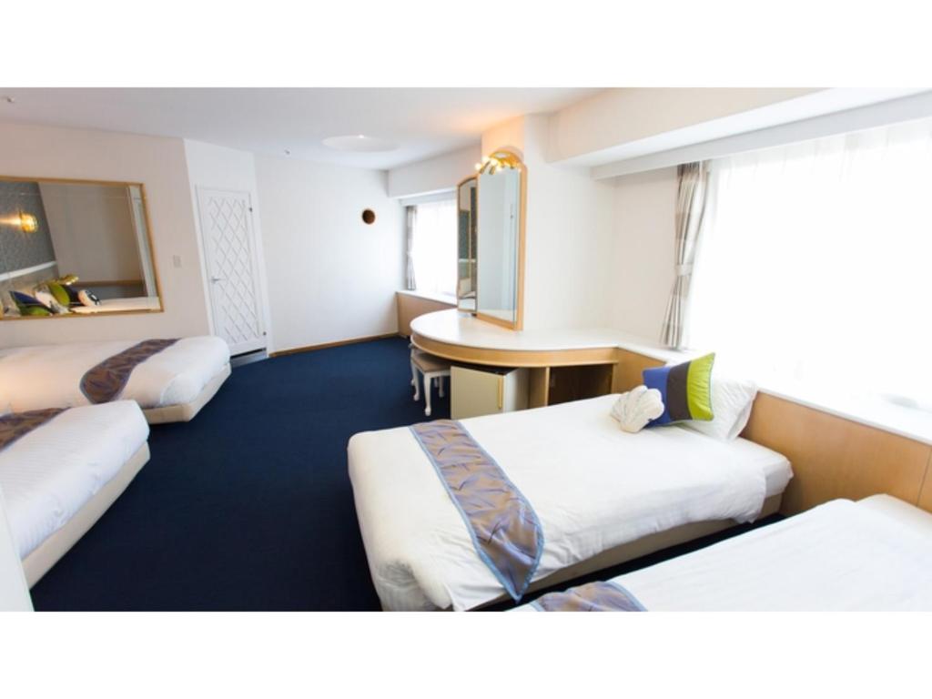 una camera d'albergo con 3 letti e una scrivania di Hotel AreaOne Sakaiminato Marina - Vacation STAY 09688v a Sakaiminato