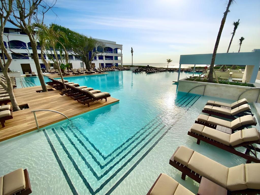 a swimming pool with lounge chairs in a resort at Hard Rock Hotel Riviera Maya- Heaven Section (Adults Only) All Inclusive in Puerto Aventuras