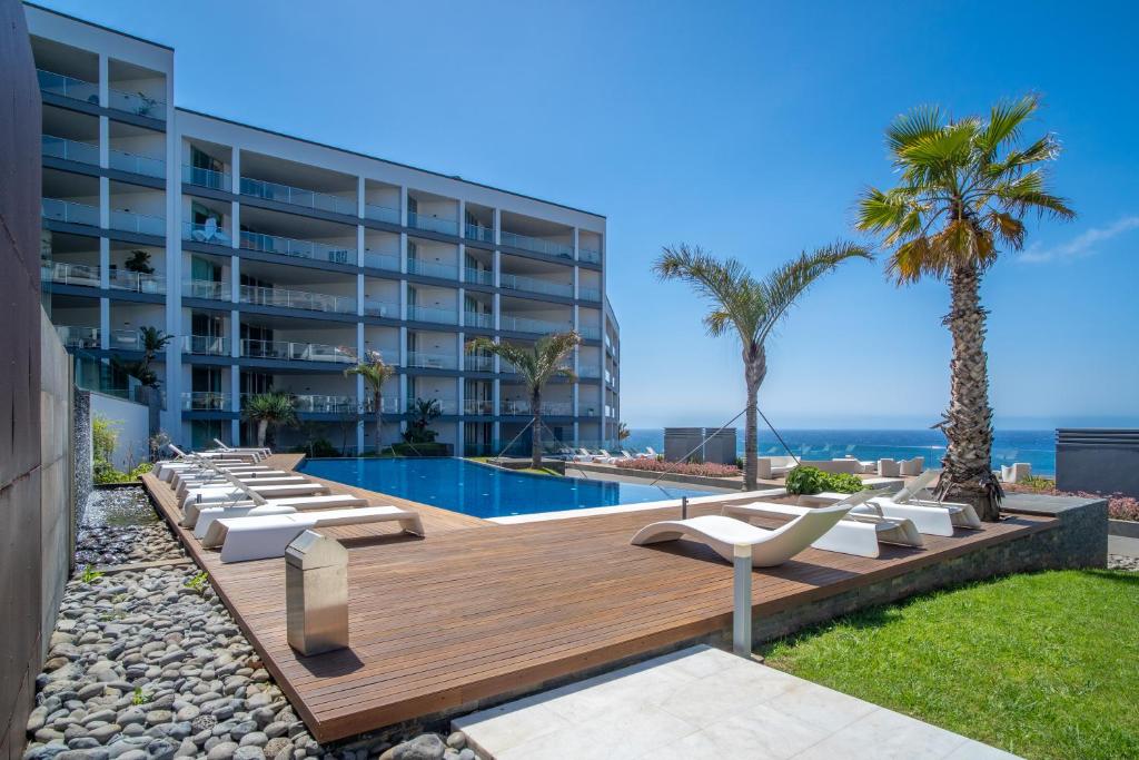 een resort met een zwembad en stoelen en een gebouw bij Madeira Palace Charles in Funchal