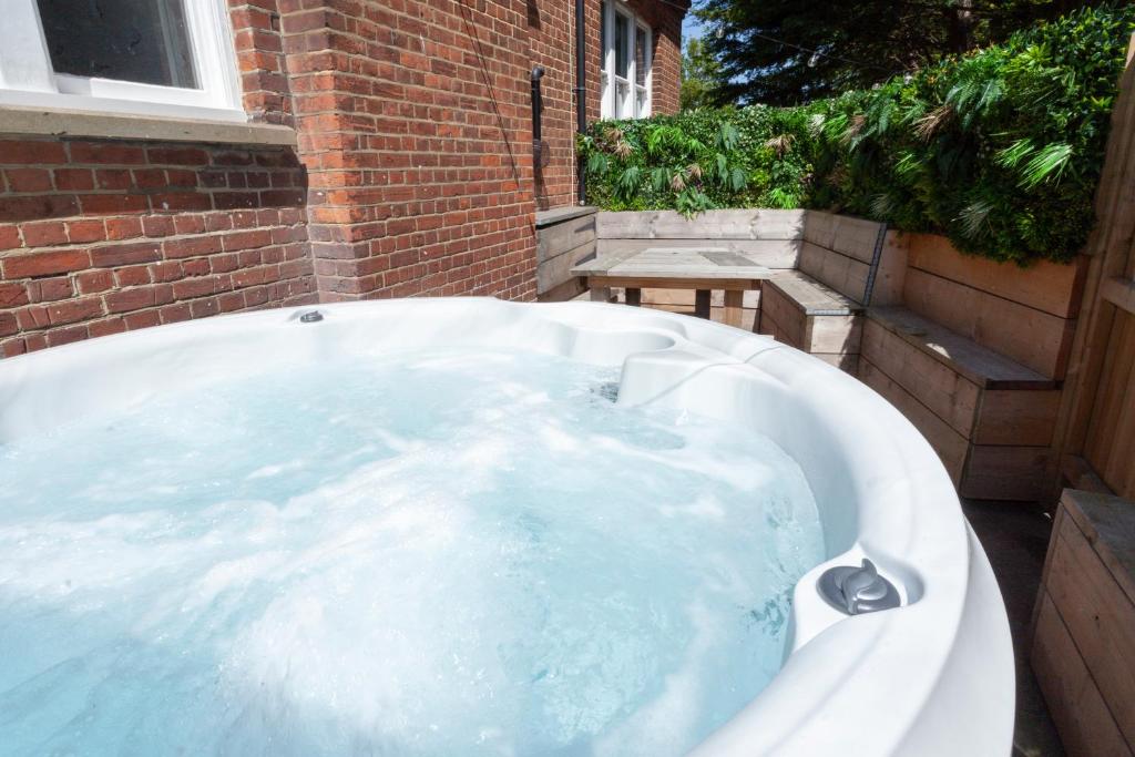 un jacuzzi en el patio trasero de un edificio en 2 The Old Schoolhouse: En-suite, hot tub, parking, pets, en Whitstable