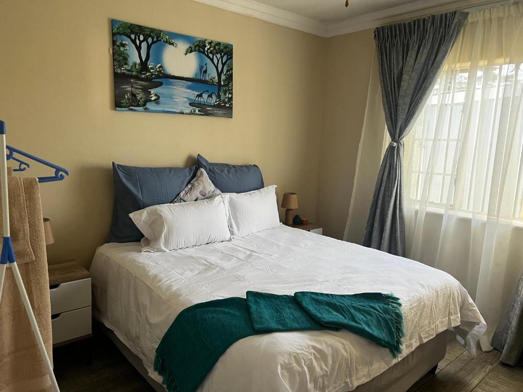 Phindulo Bed and Breakfast - No Loadshedding, Smart TVs & unlimited free fibre wifi في كروغرسدورب: غرفة نوم مع سرير مع بطانية خضراء عليه