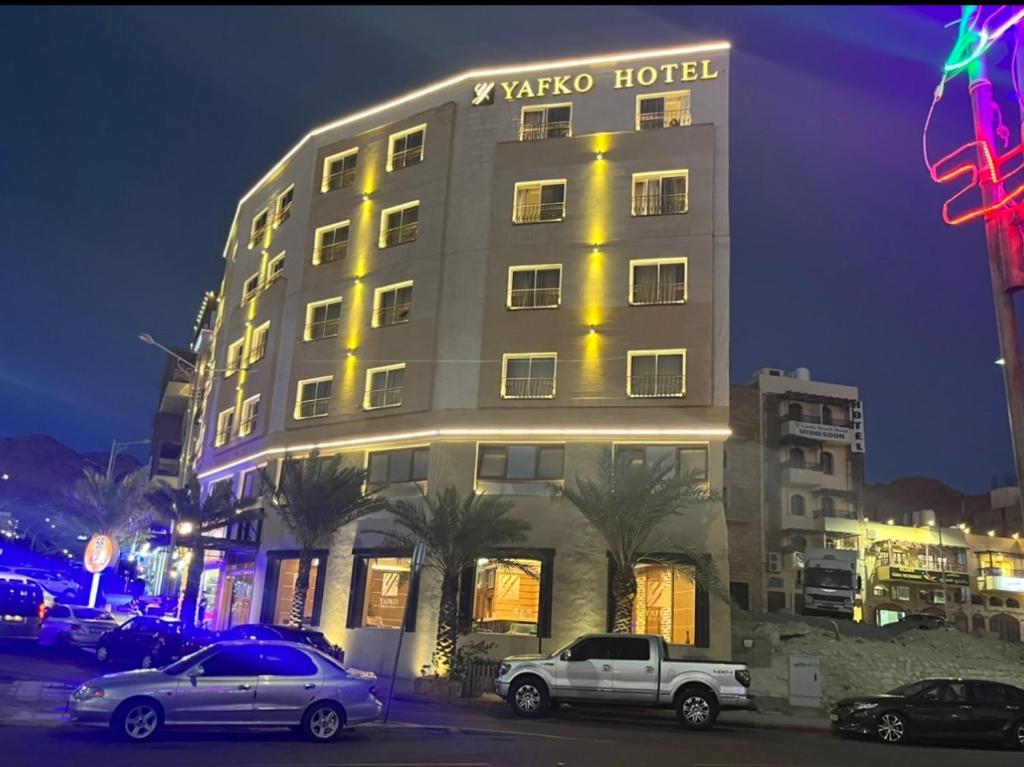 a hotel with cars parked in front of it at night at Yafko Hotel in Aqaba