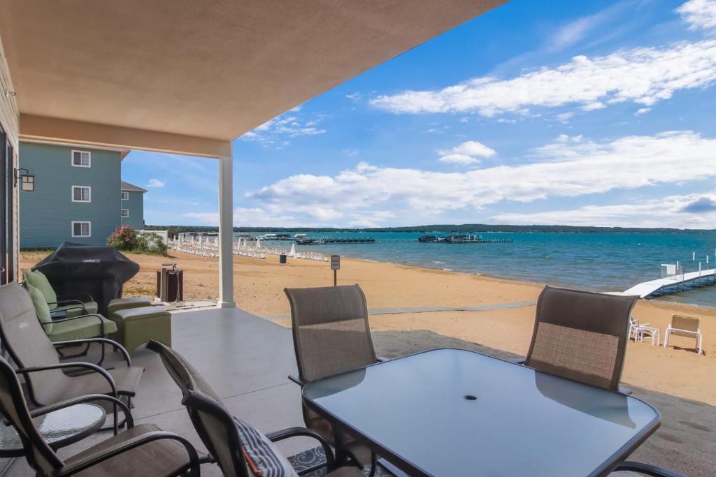 a patio with a table and chairs and a beach at Sugar Beach Villa 1012 Luxury Waterfront Condo in Traverse City