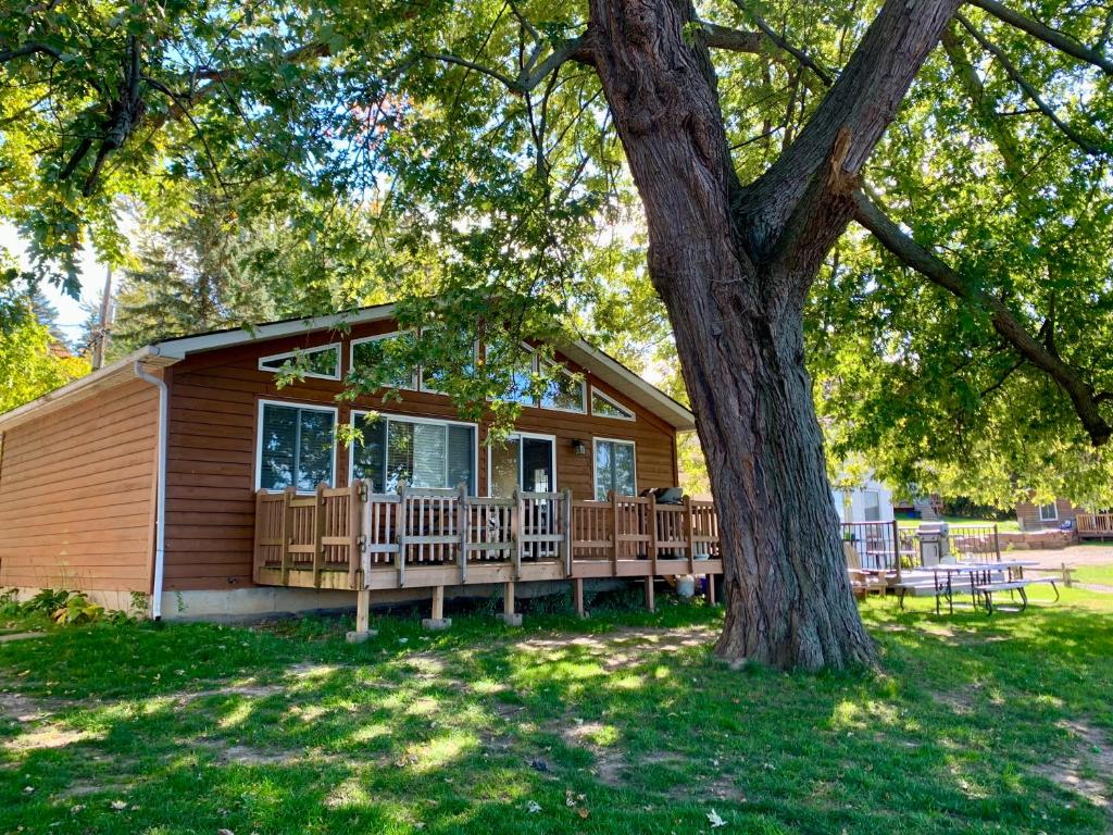 a log cabin with a deck and a tree at Merland Park Cottages and Motel in Picton