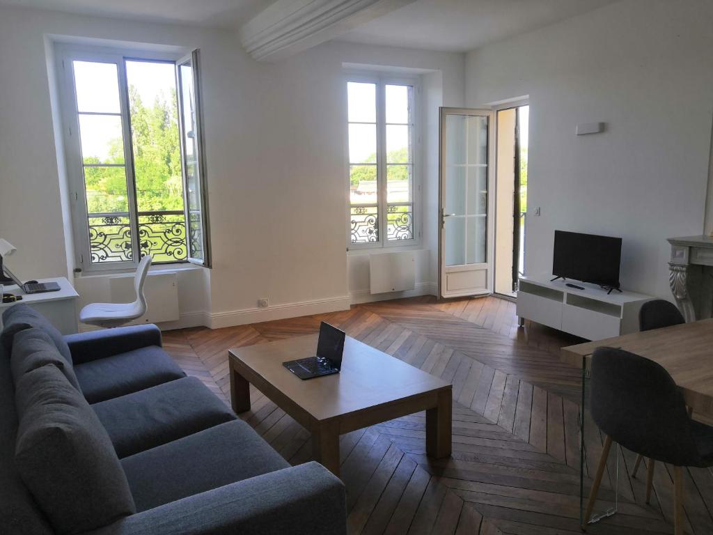 uma sala de estar com um sofá e uma mesa em Grand 2P Terrasse bord de seine em Mantes-la-Jolie